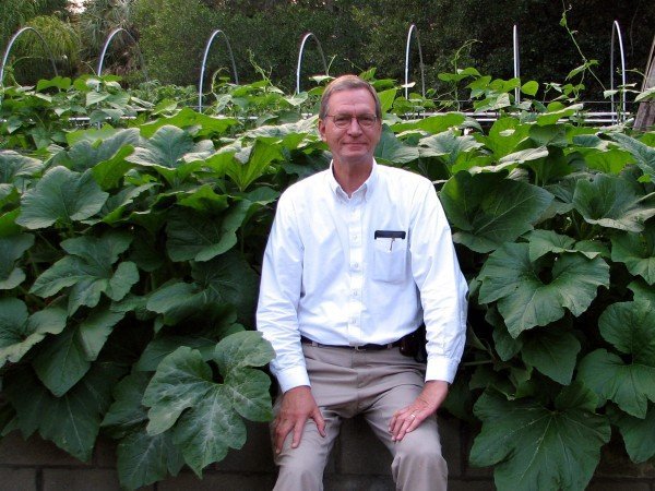 Stephen Clay McGehee in front of squash plants in raised bed garden.