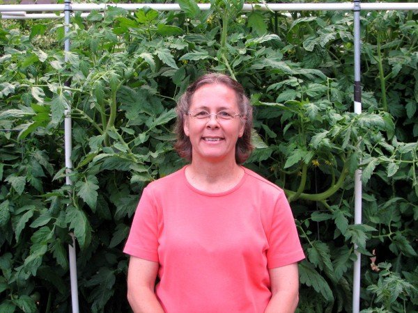 Laura McGehee in front of tomato plants in raised bed garden.